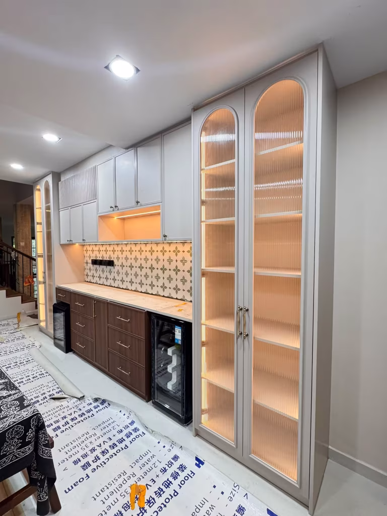Tse7en built-in display cabinet with illuminated fluted glass panels, upper storage cabinets, and wood drawers with patterned tile backsplash